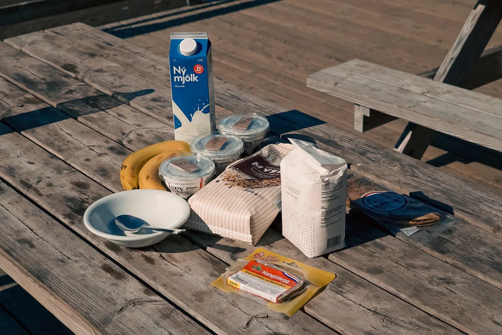 Milk, skyr tubs, fruit and bread arranged on a wooden table for a trek breakfast