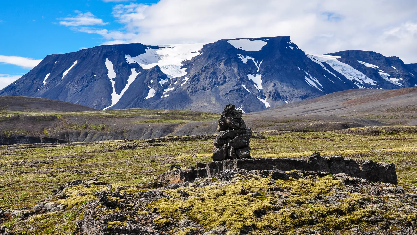 A stone cairn in open Icelandic Highland country beneath a mountain