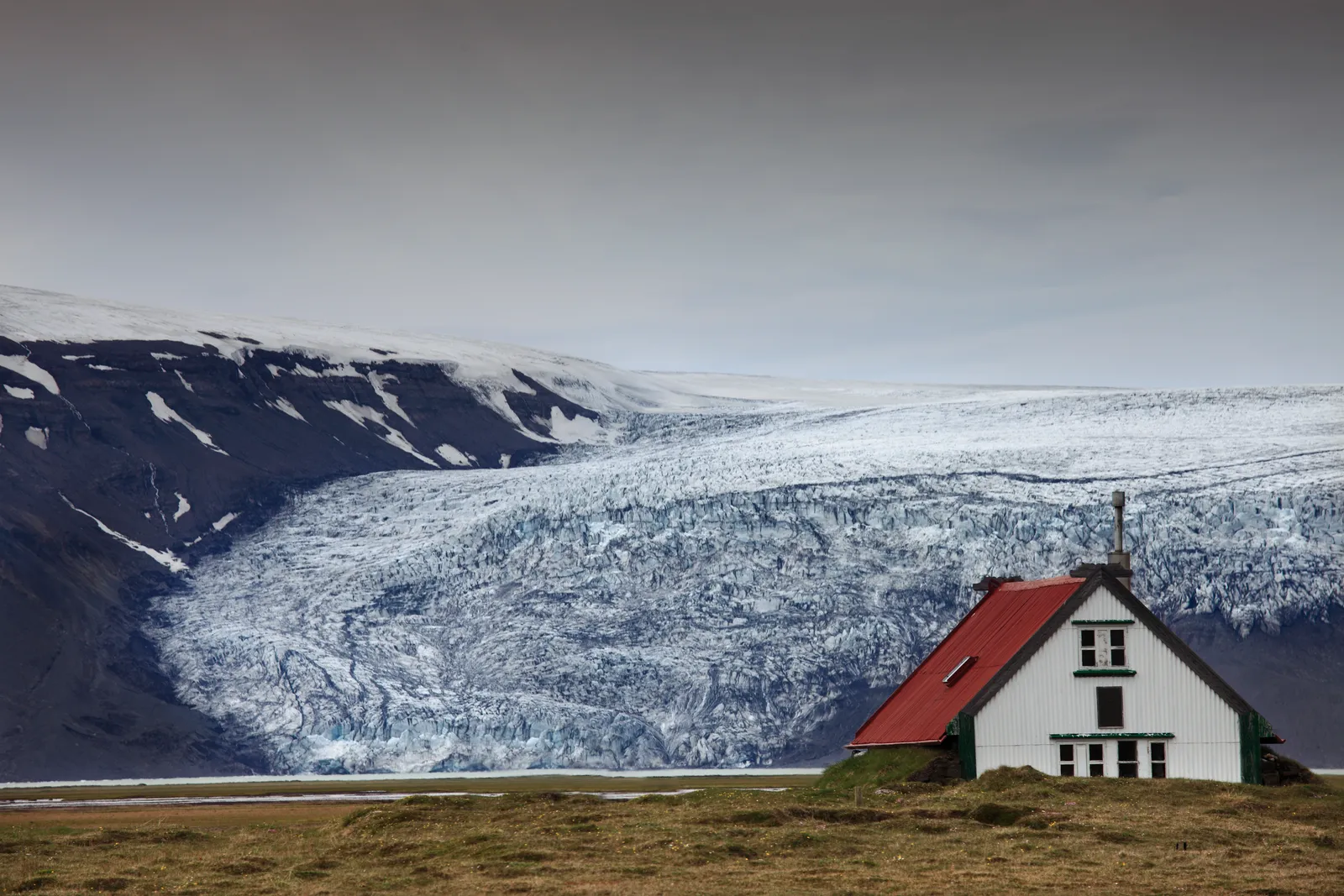 The white, red-roofed Hvítárnes hut with Langjökull glacier behind it