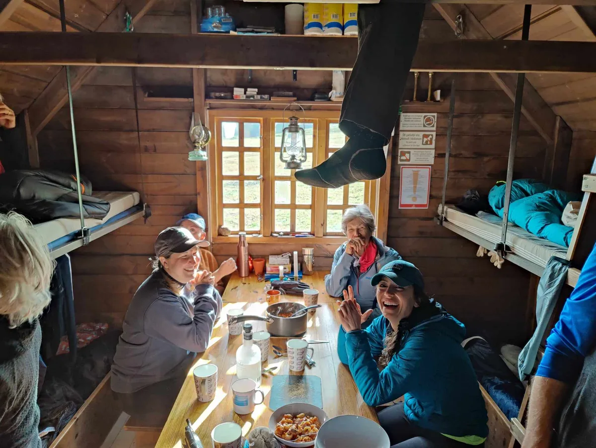 Hikers sharing a meal at a table between the bunks in Þjófadalir hut