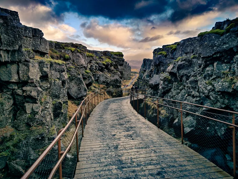 A footpath and wooden bridge leading into the rocky rift at Þingvellir