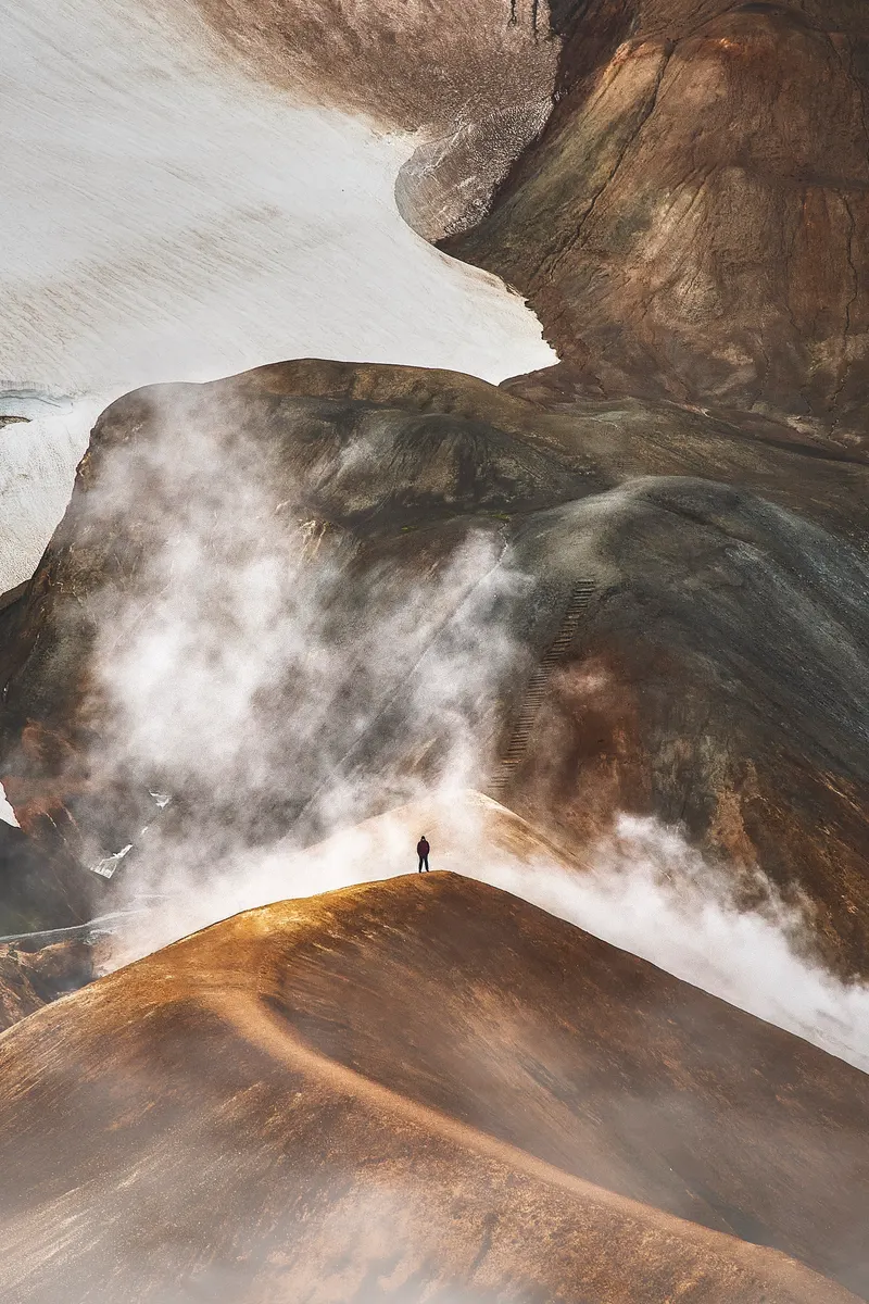 A lone hiker among steaming rhyolite slopes in Kerlingarfjöll
