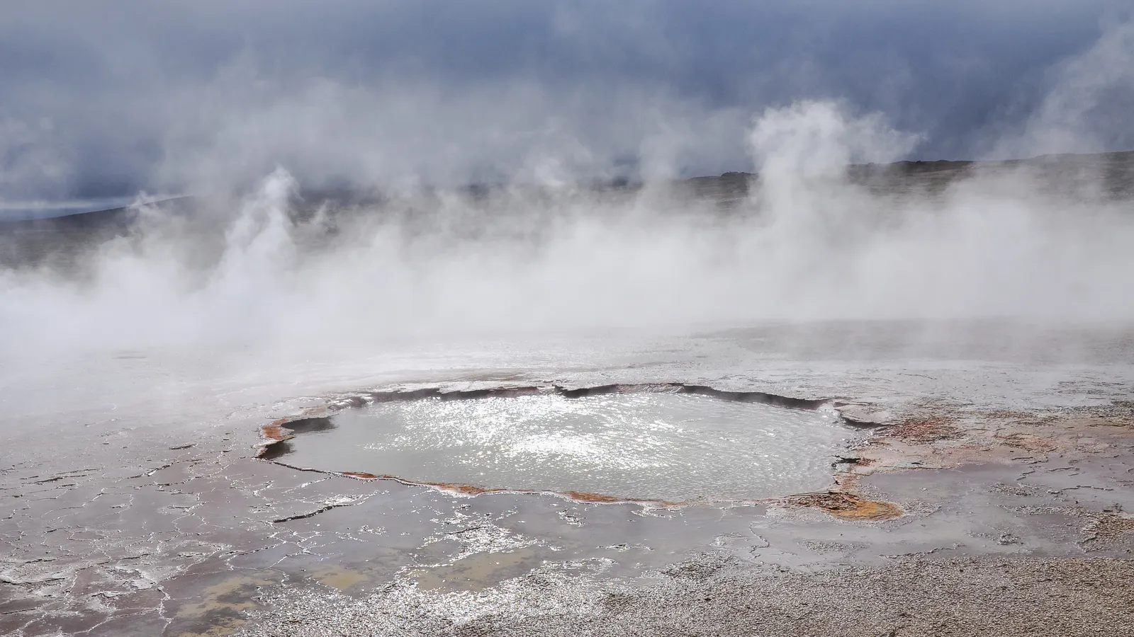 Steam rising above a hot pool surrounded by pale mineral deposits at Hveravellir