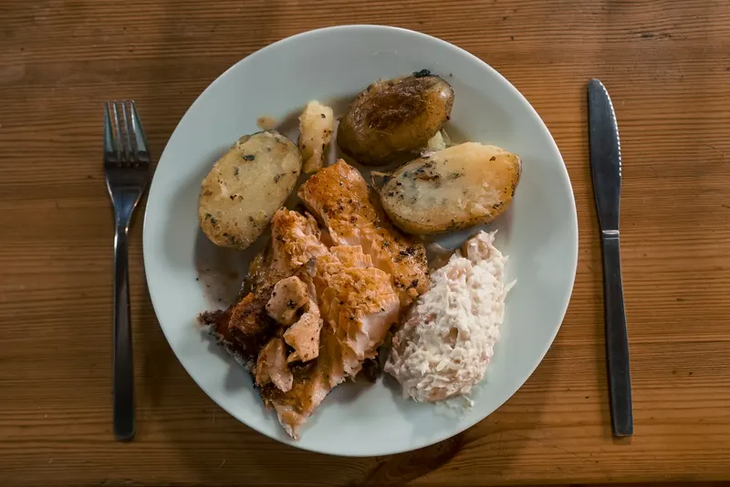 A plate of Arctic char, roasted potatoes and salad photographed from above