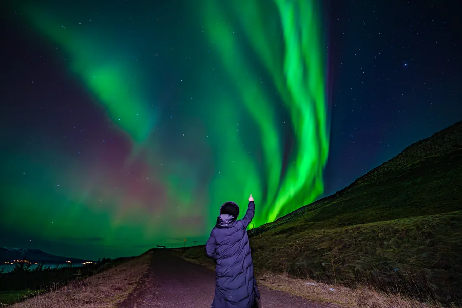 A guest pointing at sharply defined green curtains over a hillside