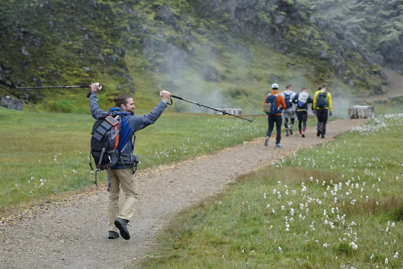 A hiker raising his trekking poles as the group walks through Landmannalaugar