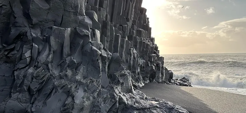 Basalt columns beside the black sand and breaking Atlantic waves at Reynisfjara
