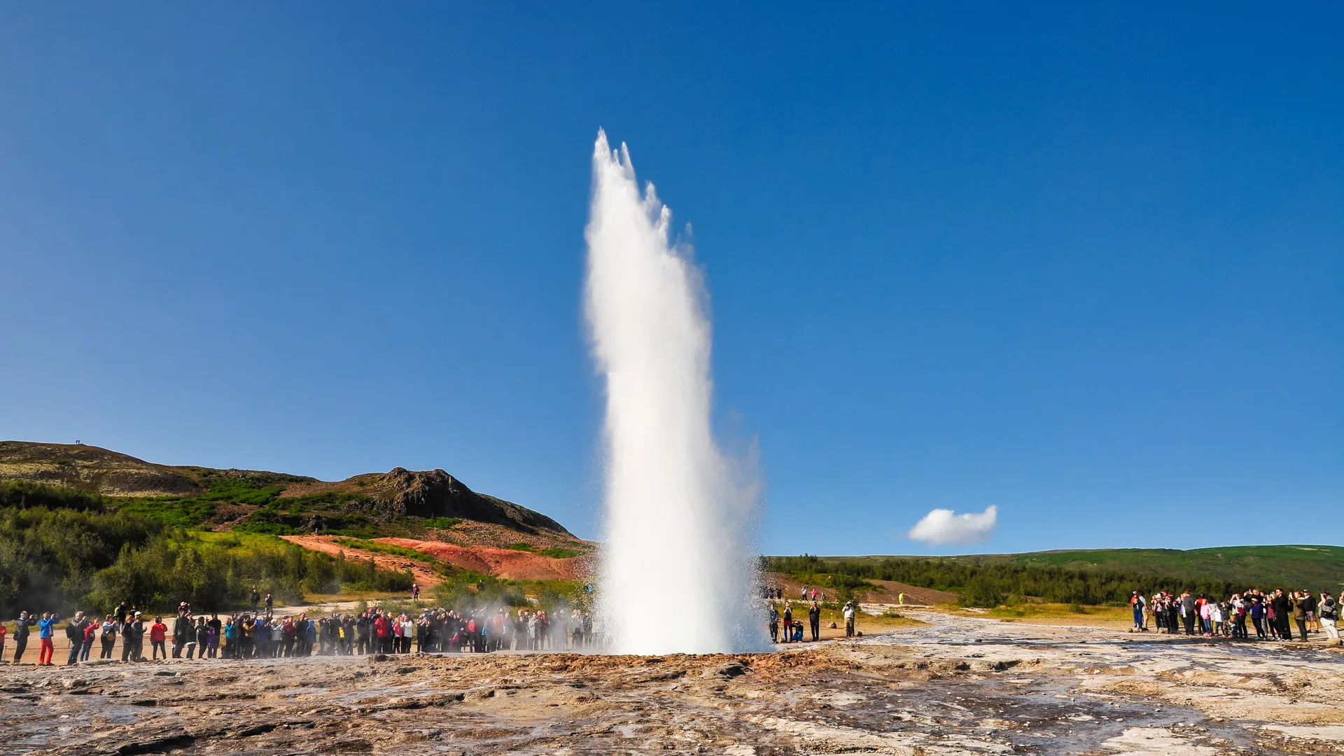 Strokkur erupting under a blue sky in the Geysir geothermal area