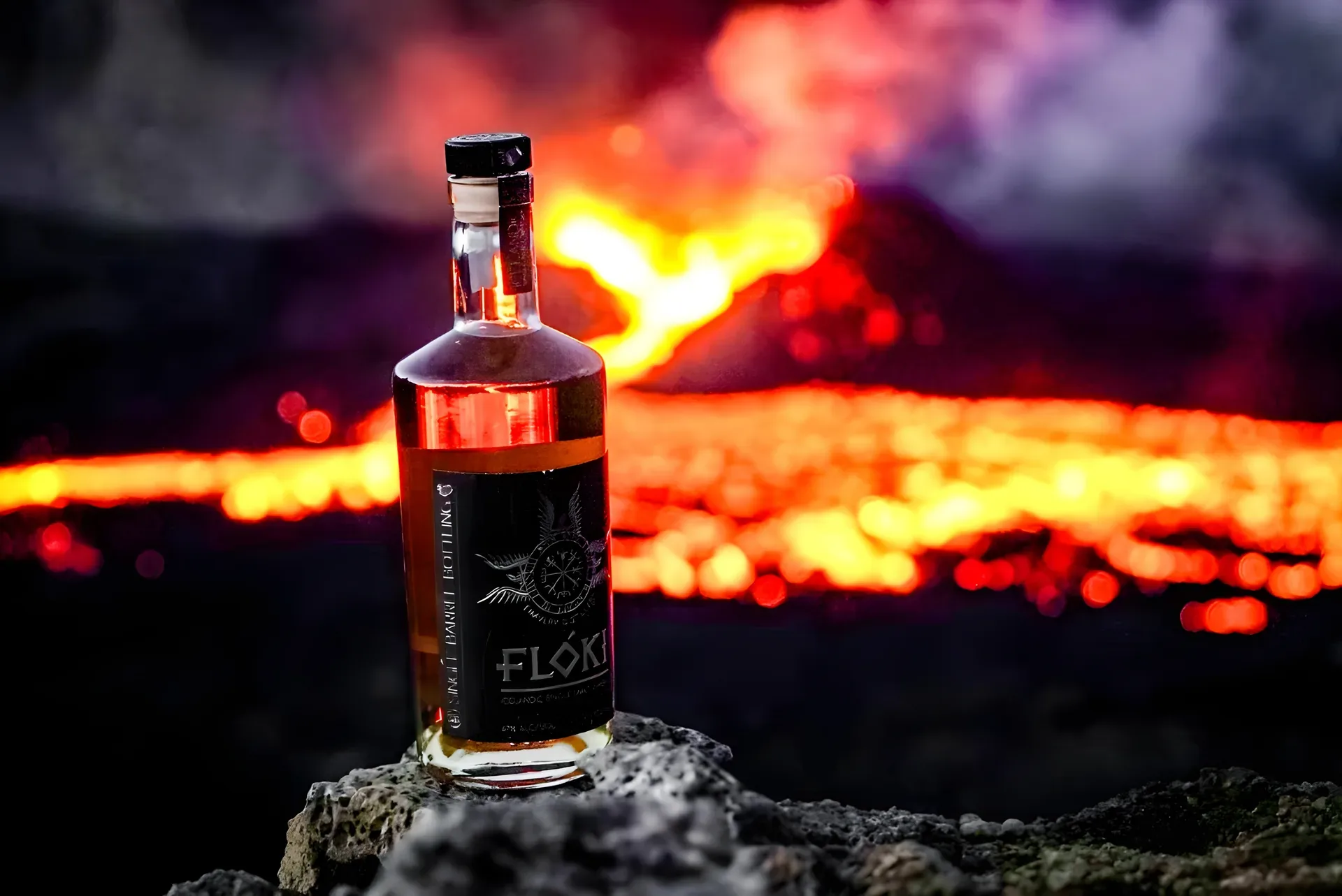 A Floki Whiskey bottle standing on a lava rock in front of an active volcanic eruption
